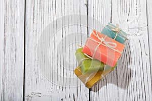 Stack of colorful scented soap bars with brown ribbon on wooden background