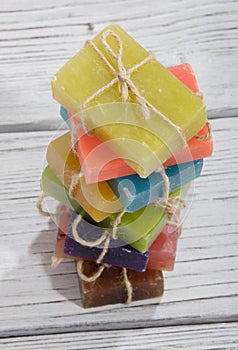 Stack of colorful scented soap bars with brown ribbon on wooden background