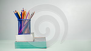 Stack of colorful textbooks and a glass of bright pencils on a white background, Concept of education, training, School tools,