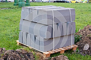 Stack of concrete curbs on a green lawn