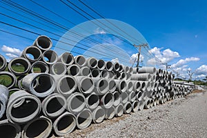 Stack of concrete drainage pipes for wells and water discharges with blue sky