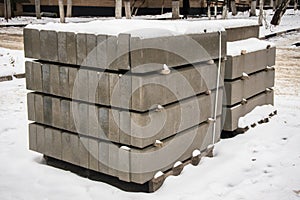 Stack of concrete road curbs in a yard for the overhaul of a sidewalk, organised by municipal public utility service.