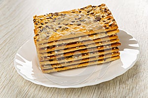 Stack of cookies with sunflower seeds, flaxseeds and sesame in plate on table