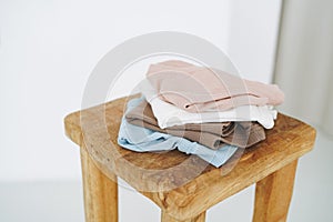 Stack of cotton tops in natural tones on wooden chair in bright room