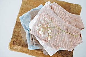 Stack of cotton tops in natural tones on wooden chair in the bright room, view from top