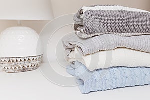 Stack of cozy comfortable homely knitted sweaters in pastel colors, cosy homelike clothes concept with copy space