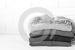 Stack of cozy knitted sweaters in gray preparing for winter cold concept black and white photo.