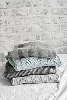 Stack of cozy winter autumn sweaters pullovers on the table on a light background photo