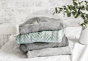 Stack of cozy winter autumn sweaters pullovers on the table on a light background photo