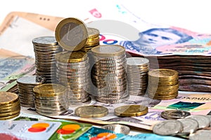 Stack of credit cards with Ukrainian hryvnia cash and euro coins, close-up view.