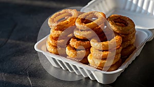 Stack of Crispy Onion Rings in Takeout Container
