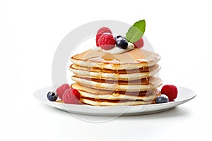 A stack of delicious fluffy pancakes decorated with blueberries and raspberries, drizzled with maple syrup or honey