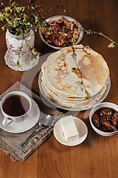 Stack of delicious homemade pancakes or blini, cup of tea, butter