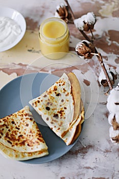 Stack of delicious homemade pancakes on plate with honey, sour cream and tea. Breakfast. Rustic style, close up top view. Flat lay