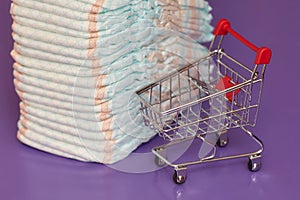 Stack of diapers or nappies and mini shopping cart, concept