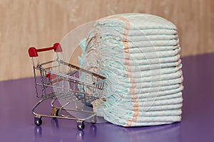 Stack of diapers or nappies and mini shopping cart, concept