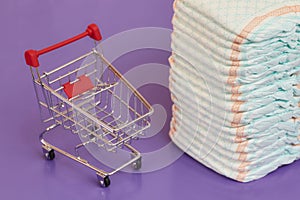 Stack of diapers or nappies and mini shopping cart, concept