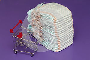 Stack of diapers or nappies and mini shopping cart, concept