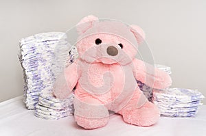 Stack of diapers or nappies with pink teddy bear
