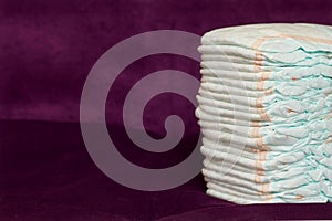 Stack of diapers or nappies on purple background
