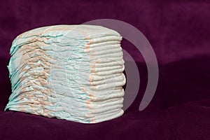 Stack of diapers or nappies on purple background