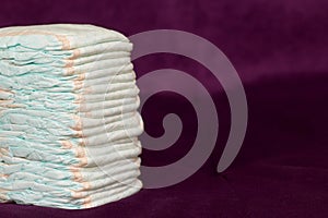 Stack of diapers or nappies on purple background