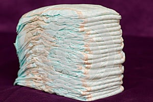 Stack of diapers or nappies on purple background