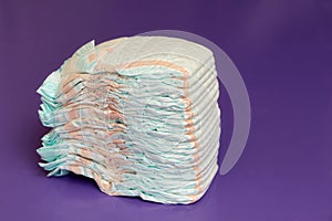 Stack of diapers or nappies on purple background