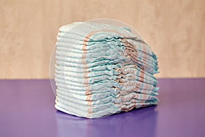 Stack of diapers or nappies on purple background