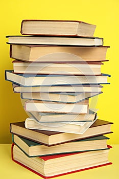 Stack of different hardcover books on background