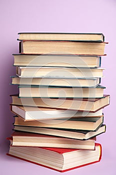 Stack of different hardcover books on violet background