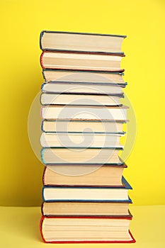 Stack of different hardcover books on yellow