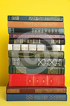 Stack of different hardcover books on yellow