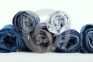 Stack of different rolled jeans on white background