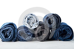 Stack of different rolled jeans on white background