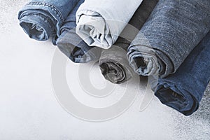 Stack of different rolled jeans on white background
