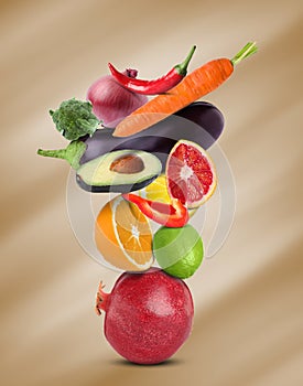 Stack of different vegetables and fruits on pale light brown background