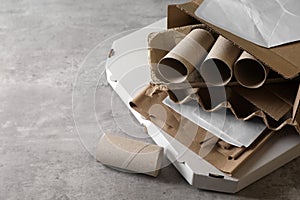 Stack of different waste paper on grey table, closeup. Space for text