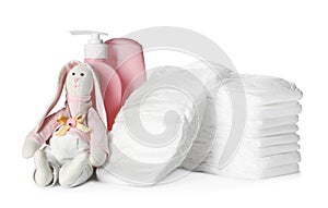 Stack of disposable diapers, toy bunny and toiletries on background