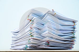 Stack of document paper with colorful paperclip place on wooden table and white background