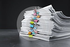 Stack of documents with binder clips on grey stone table