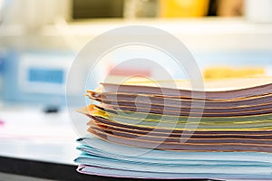 Stack of documents in multicolored paper files on desktop in office