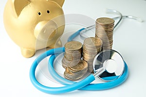 Stack of dollars money with stethoscope and gold piggy bank on white background