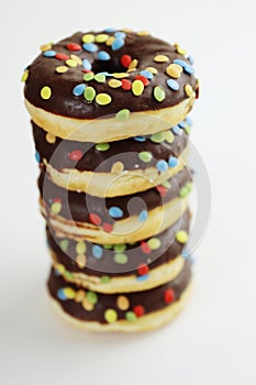 A stack of doughnuts glazed with chocolate and colorful smarties. Pile of 5 donuts isolated on a white background. Side view. Copy