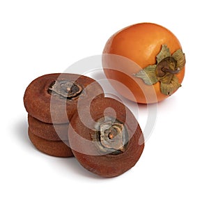 Stack of dried kaki persimmon and a fresh one on white background close up