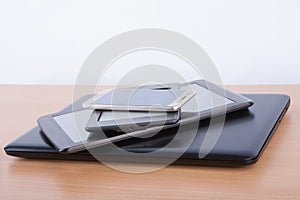 Stack of electronic gadgets on a table - notebook, tablet, ebook reader and a smatphone