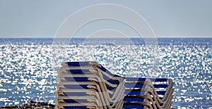 Stack of empty chairs with an unobstructed view of the sunset over the ocean