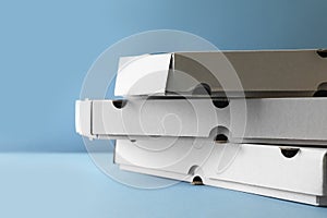 Stack of empty pizza boxes on light blue background, closeup. Space for text