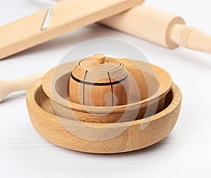 Stack of empty wooden round plates on a white table background