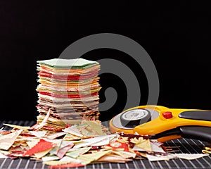 Stack english paper pieced hexagons surrounded by scraps over black background